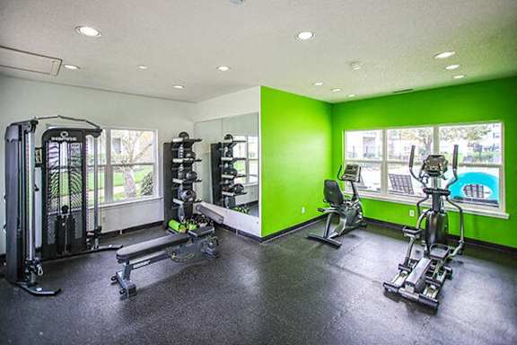 a gym with exercise equipment and green walls