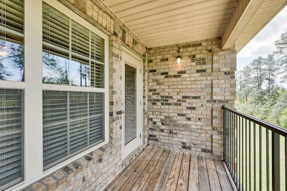 A balcony with a wooden floor and a brick wall.