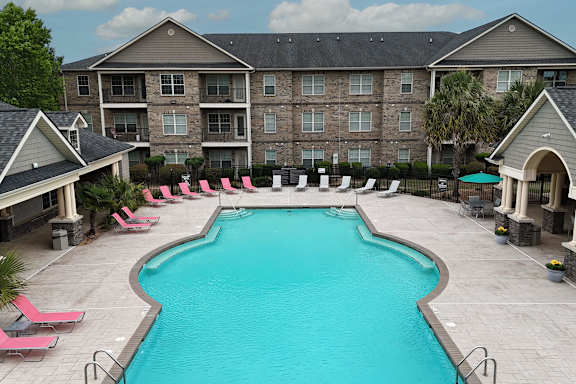 A large swimming pool surrounded by pink lounge chairs and umbrellas.