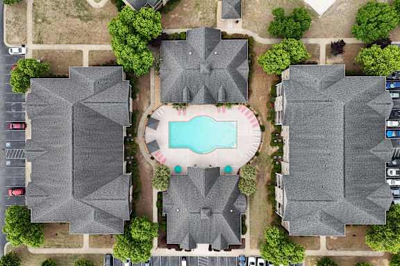 A bird's eye view of a residential area with houses and a swimming pool.