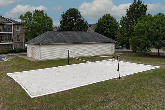 A white tennis court with a black net and a black pole.