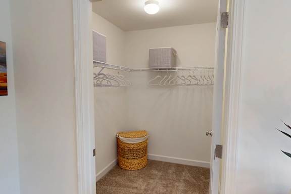 A small closet with a basket on the floor.