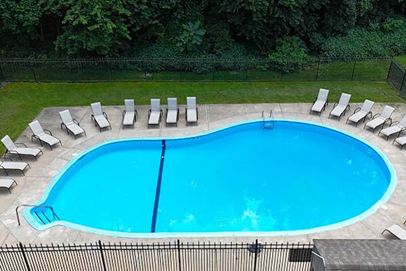 A large blue swimming pool surrounded by white lounge chairs.