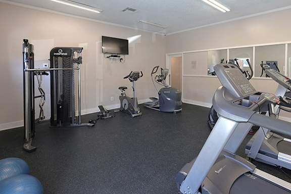 A gym with a variety of exercise equipment including treadmills, stationary bikes, and weight machines.