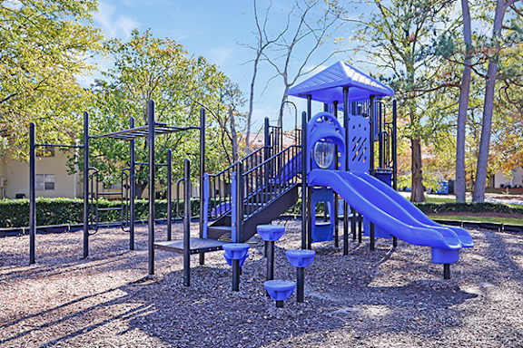 A playground with a blue slide and a wooden structure.
