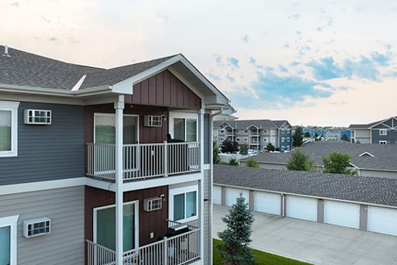 A balcony of a two-story apartment building with a view of other buildings in the background.