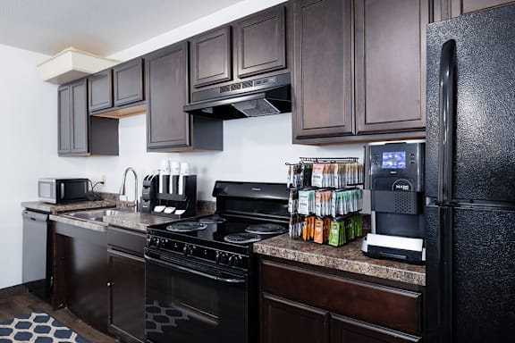 A kitchen with black appliances and brown cabinets.