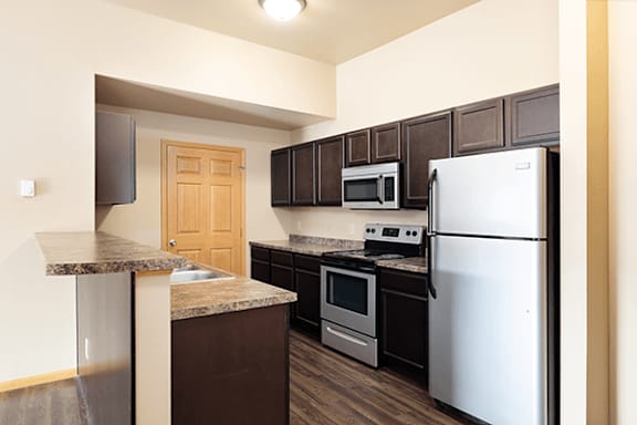 A kitchen with a white refrigerator, brown cabinets, and a granite counter.