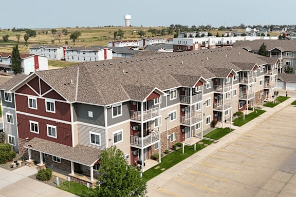 Apartment complex with a parking lot in front.