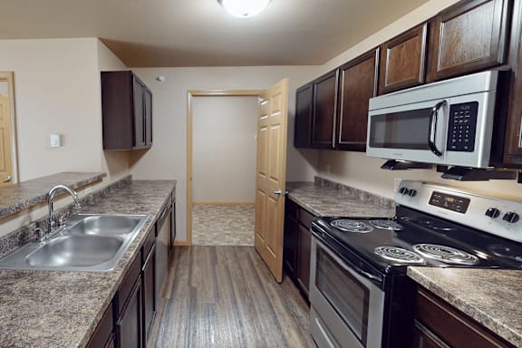A kitchen with a stove, sink, and cabinets.