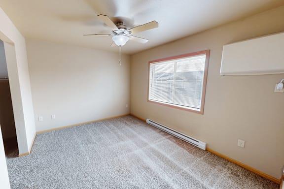 A room with a ceiling fan and a window with blinds.