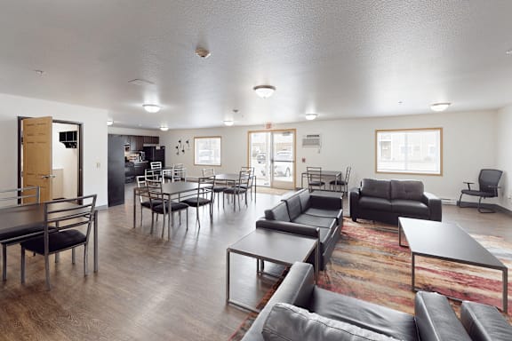 A living room with black leather furniture and a wooden floor.