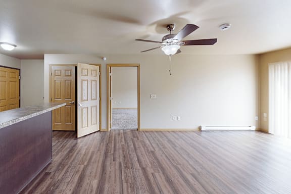 A room with a ceiling fan and wooden floors.