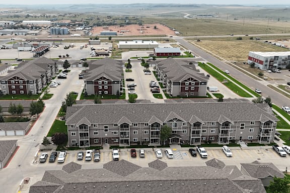 A large apartment complex with a parking lot in front.