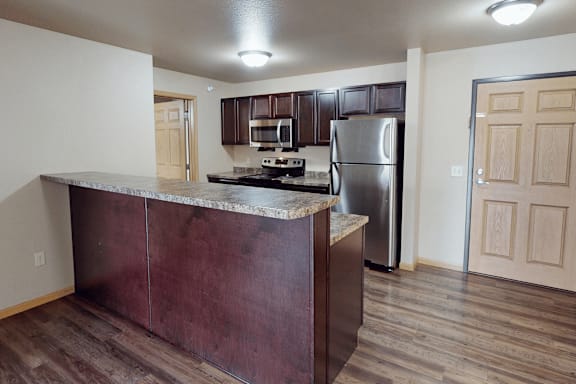 A kitchen with a refrigerator, stove, and cabinets.