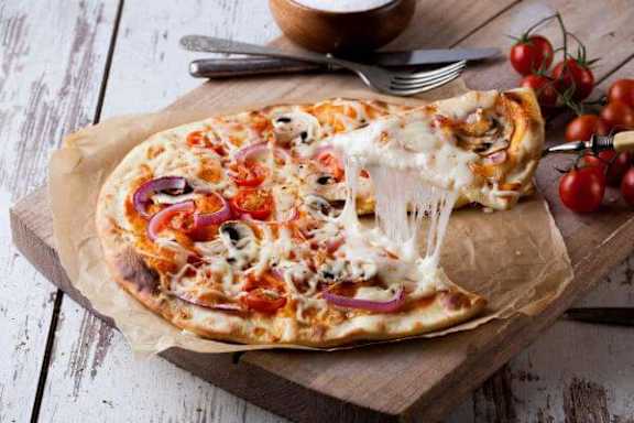 A pizza with tomato slices and basil leaves on top.