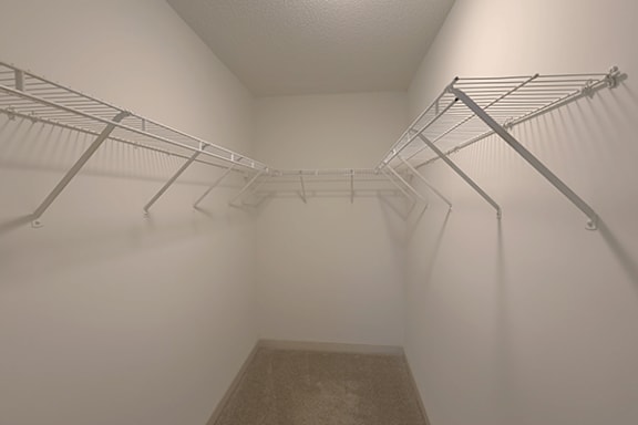 A walk-in closet with metal racks and a carpeted floor.