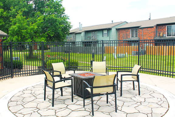 a patio with a table and chairs in front of a fence