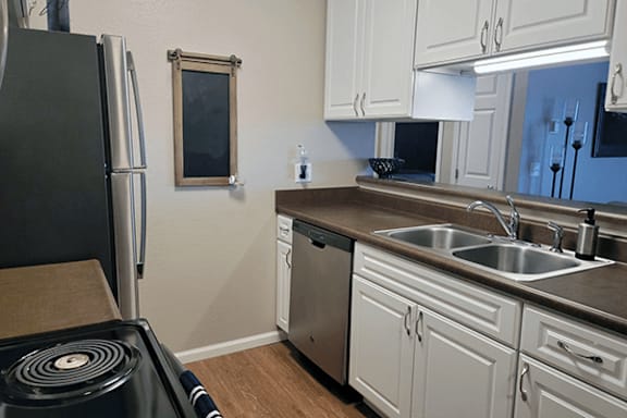 A kitchen with a black refrigerator and white cabinets.