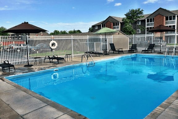 A small pool surrounded by a fence and chairs.