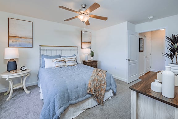 A bedroom with a bed, nightstand, and a ceiling fan.