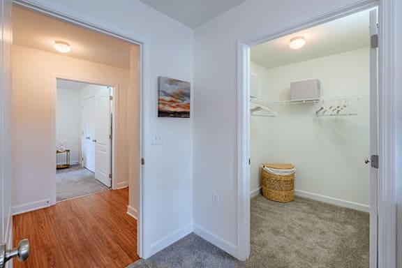 A room with a wooden floor and a white wall with a painting hanging on it.
