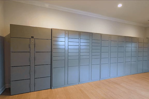 A room with a wall of package lockers and a wooden floor.