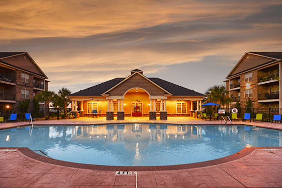 A large swimming pool in front of a building with a sunset in the background.