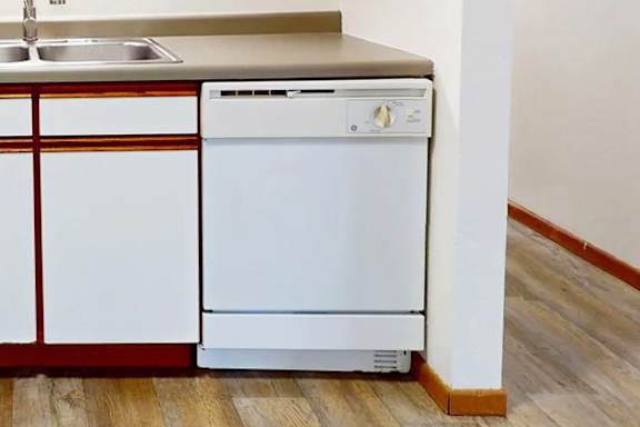 A white dishwasher is in a kitchen next to a sink.