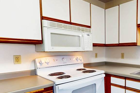 A white stove and microwave in a kitchen with white cabinets.