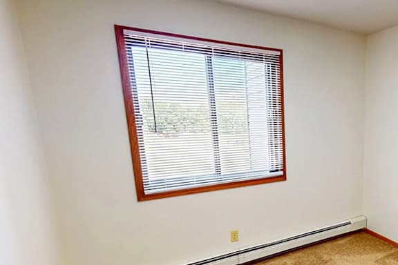 A window with blinds in a room with white walls.