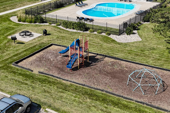 A playground with a blue slide and a red swing set.