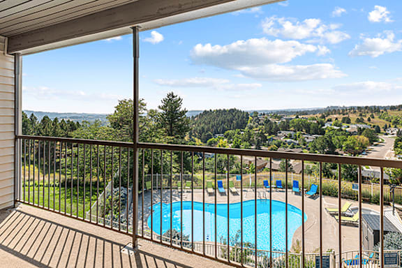 A balcony overlooks a pool and a scenic view of the countryside.