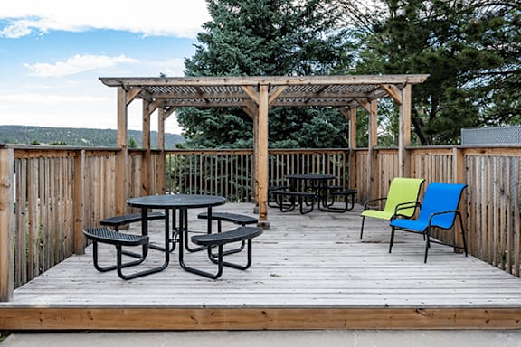 A wooden deck with a table and chairs under a pergola.