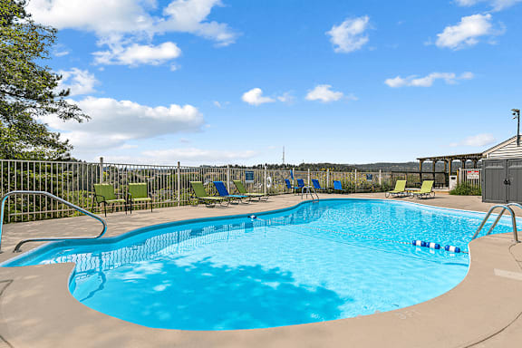 A large outdoor swimming pool with a metal fence and sun loungers.