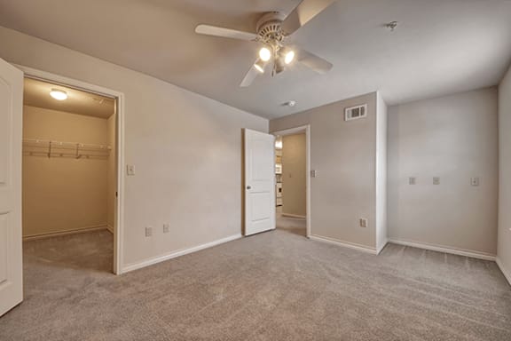 A room with a ceiling fan and carpeted floor.