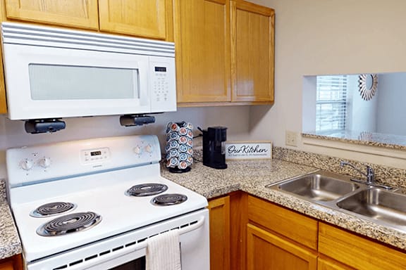 A kitchen with a white stove and a white microwave above it.