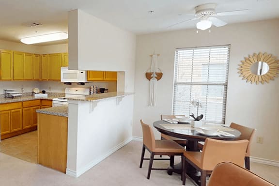 A kitchen with a table and chairs in front of a window.