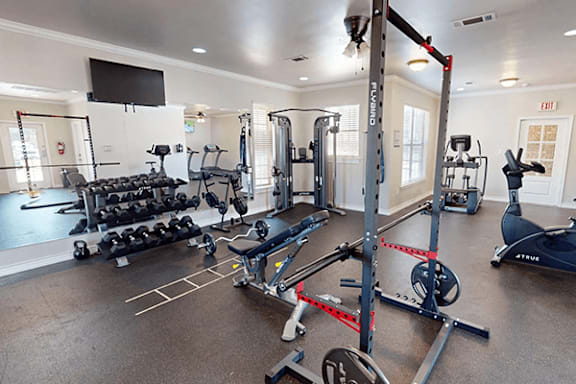 A gym with a variety of equipment including weights, a treadmill, and a stationary bike.