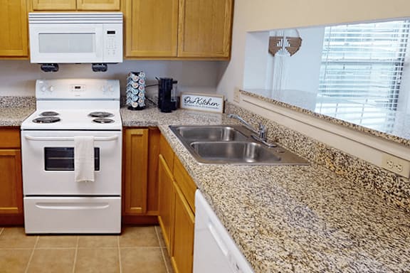A kitchen with a white stove and a granite counter.
