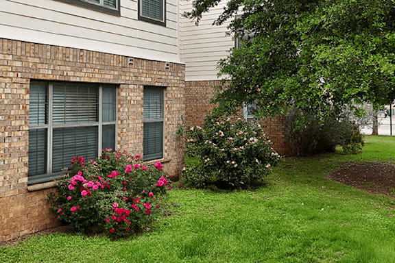 A brick building with a window and flowers in front.