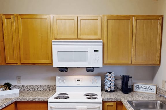 A kitchen with a white stove and wooden cabinets.