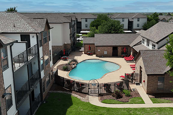 A small pool surrounded by a black fence and red chairs.