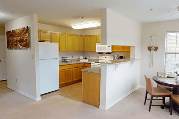 A kitchen with white appliances and wooden cabinets.