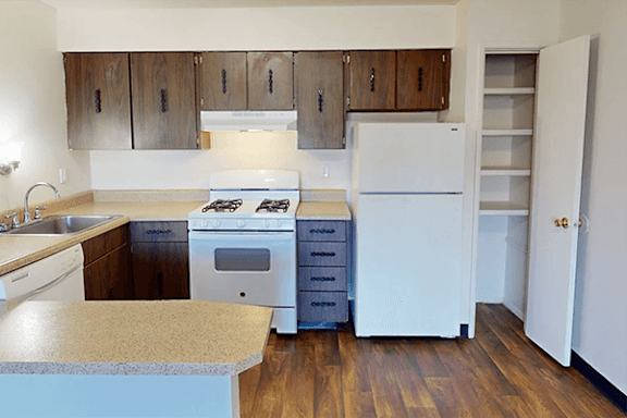 A kitchen with white appliances and wooden cabinets.