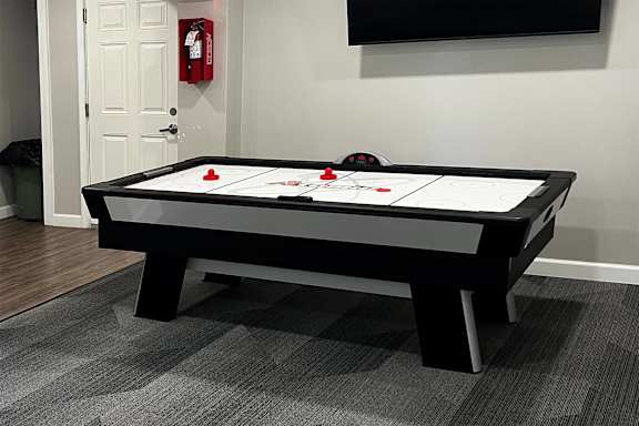 A black air hockey table with red pucks in the middle.