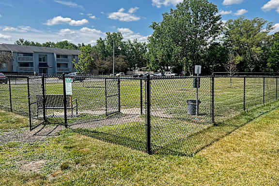 A baseball field with a fence and a trash can.