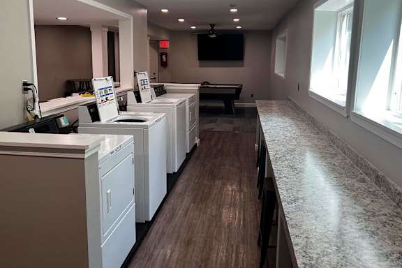 A laundromat with washers and dryers lined up.