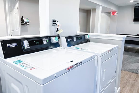 a laundry room with two washers and a dryer