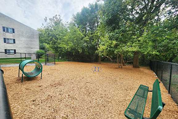 A playground with a green slide and two green benches.